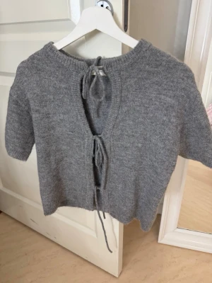 Grå stickad topp med knytning  - Snygg grå stickad topp med korta ärmar och som knyts med 3 band. Mjuk och skön💞