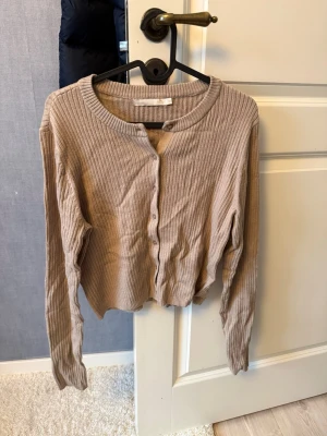 Kofta från lager157 - En beige/brun kofta från lager 157. Mjukt ribbat material med knappar. Strl S/M. Aldrig använd, i nyskick! 