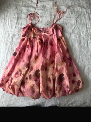 Rosa blommig kortklänning från Nakd - Finns inte kvar att köpa i butik. Så fin kort blommig sommarklännig med ballongformadkjol. Det står storlek 42 men den passar s/m. 