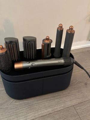 Dyson Airwrap multistyler koppar - Säljer en Dyson Airwrap multistyler i koppar och grått med flera olika stylingtillbehör. Setet innehåller borstar och cylindrar för att skapa lockar, volym och släta frisyrer. Allt kommer i en snygg svart förvaringsbox. Perfekt för dig som vill fixa håret på olika sätt. Använd max 5 gånger!