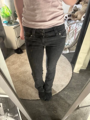 Svarta lågmidjade jeans från berskha - Snygga svarta lowwaist jeans med dubbla knappar i midjan och klassiska fickor både fram och bak. 