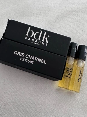 BDK Gris Charnel Extrait parfymprov - Två små parfymprover av BDK Parfums Gris Charnel Extrait. Flaskorna är genomskinliga med svart lock och innehåller guldfärgad vätska. Kommer i en elegant svart kartong med vit text. Perfekt för dig som vill testa en exklusiv doft. Oanvända 