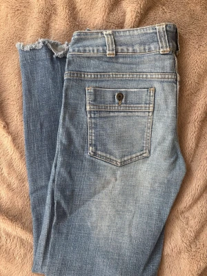 Vintage jeans - PRIS GÅR ATT DISKUTERA. Snygga ljusblå vintage jeans med raka ben och trendiga råa benslut. Klassisk femficksmodell med knappstängning och bälteshällor. Jeansen har en bakficka med knapp och slitna detaljer för en avslappnad look. Perfekta för dig som gillar en cool och avslappnad stil. Köpta mellan 1985-2005 så därav går dom inte längre att få tag på💗