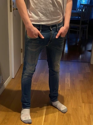 Blå slim fit jeans med slitningar - Snygga blå replay slim fit jeans med ljusa slitningar och tvättade detaljer på låren och knäna. Klassisk femficksmodell med normal midja och dragkedjegylf. Perfekta för en avslappnad och trendig stil. Det replay jeans som har ett bra skick och snygga men eftersom som jag har många jeans vill jag sälja av lite 