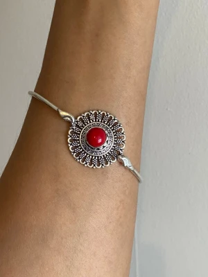 s925 sterling Silverf armband med röd pärla - Unikt armband i silverfärg med en rund, detaljerad dekoration i mitten och en röd pärla i centrum. Armbandet har en öppen design och fina mönster runt pärlan som ger en bohemisk känsla. Perfekt accessoar för att lyfta din stil. material: s925 sterling silver pläterat justerbar