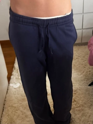 Mörkblå mjukisbyxor från gina - Mörkblå mjukisbyxor med resår i midja. Byxorna har raka ben och sidofickor. Perfekta för chill dagar eller när du vill vara extra bekväm. Troligtvis i mjukt bomullsmaterial.