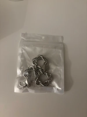 Cordell armband (Silver 10mm 20cm) - Säljer ett chunky armband i silverfärgad metall med tvinnad kedjedesign. Armbandet har en robust karbinhake som lås och en modern, stilren look. Perfekt accessoar för att lyfta din outfit.