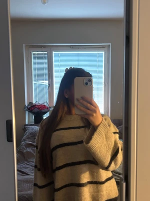 Beige stickad tröja med svarta ränder - Säljer en beige stickad tröja från Gina Tricot med svarta horisontella ränder, som tyvärr inte kommer till användning längre. Tröjan har rund halsringning, långa ärmar och ribbade muddar. Perfekt för att skapa en avslappnad och trendig look.