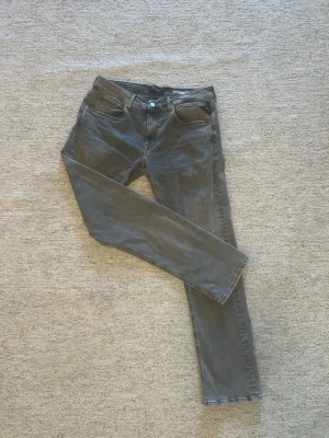 Gråa Replay Grover jeans straight fit - Snygga gråa jeans från Replay, modell Grover med straight fit. Jeansen har fem klassiska fickor, bälteshällor och silverfärgad knapp. Tillverkade i stretchigt Hyperflex-material för extra komfort.