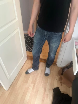 Blå raka jeans herr - Säljer ett par klassiska blå jeans med rak passform och normal midja. Jeansen har fem fickor och subtila slitningar för en avslappnad look. Perfekta till vardags och passar till det mesta. Materialet är denim i bomull.