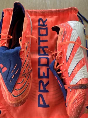 Adidas Predator orange fotbollsskor - Adidas Predator Elite Fold-over Tongue FG Coral Blaze - Orange/Vit/Beam Orange. Endast använda fyra träningar innan de blev för små. Nypris 1649:- Kvitto finns. Inköpta 4/5-26. Påsen följer med. 
