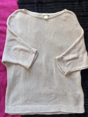 Ljusrosa stickad tröja från H&M - En ljusrosa stickad tröja från H&M med trekvartsärmar och avslappnad passform. Tröjan har rund halsringning och är tillverkad i ett mjukt, tunt stickat material som passar perfekt för lager-på-lager-stil.