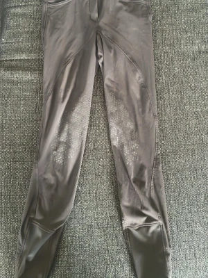 Svarta leggings med mönstrade detaljer - Säljer ett par svarta leggings med coola mönstrade detaljer på låren. De har en slimmad passform och är tillverkade i ett stretchigt material som ger bra komfort. Perfekta för dig som gillar en sportig och stilren look.