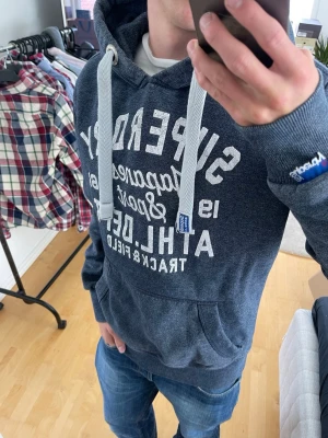 Blå hoodie från Superdry - Säljer nu denna sjukt snygga Vintage 2000s SuperDry hoodie! Passar till allt och har en perfekt passform. Säljs ej längre i butik och är därav mycket eftertraktad😊 passar M perfekt ! Skriv vid funderingar 🤝