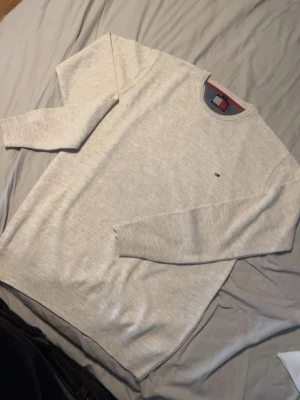Ljusgrå tröja Tommy Hilfiger - Snygg ljusgrå tröja från Tommy Hilfiger med rund halsringning och diskret logga broderad på bröstet. Klassisk och enkel design som passar till det mesta. Tillverkad i mjukt material för skön känsla.