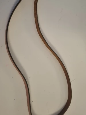 Brunt smalt läderbälte - Säljer ett smalt och stilrent bälte i brunt läder. Perfekt för att ge en clean touch till jeans eller byxor. Klassisk design utan synligt spänne på bilden, passar till många olika looks.