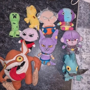 Samling av nördiga gosedjur - Säljer en samling färgglada gosedjur med motiv från olika spel och anime. Bland figurerna finns en grön Creeper, flera karaktärer från Dragon Ball och andra unika figurer. Perfekt för dig som gillar nördiga prylar och samlar på mjukisdjur.