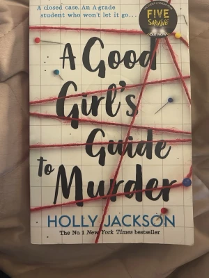 A Good Girl's Guide to Murder - Spännande thrillerbok på engelska, 'A Good Girl's Guide to Murder' av Holly Jackson. Omslaget är vitt med röd tråd och nålar som ger en true crime-känsla. Perfekt för dig som gillar mysterier och deckare. Pocketutgåva från Electric Monkey.