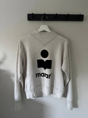Grå sweatshirt från Isabel Marant - Säljer en grå sweatshirt från Isabel Marant med stort svart logotryck på ryggen. Storlek 38. Bra kvalité. 
