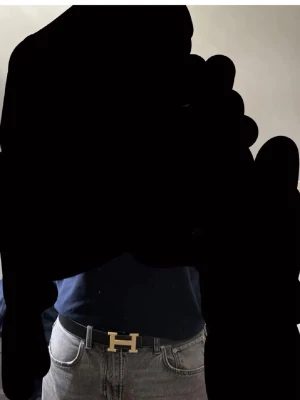 Svart H bälte med gulddetalj - Snyggt svart bälte med H med ikoniskt H-spänne i guld. Bältet har vit kontrastsöm längs kanterna. Perfekt accessoar för att lyfta vilken outfit som helst. Finns ingen box till obs!