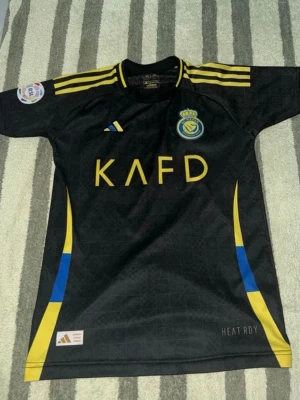 Al Nassr Ronaldo matchtröja svart - Säljer en svart Al Nassr matchtröja från Adidas. Korta ärmar och sportig passform, perfekt för fotbollsträning eller att bära som supporter. Knappt använt 