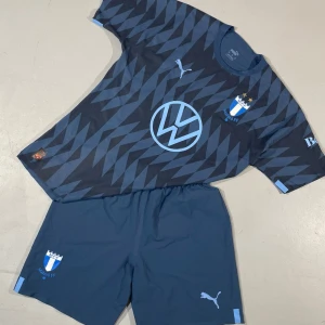 Officiellt matchställ MFF - Nypris butik ca 1,800kr ‼️                       Officiellt Malmö FF matchställ i mörkblått med ljusblå detaljer. Geometriskt mönster, klubb och sponsor logga framtill. Shortsen är av samma blå med klubbmärke och Puma logga i storlek L då M sitter för tight, shortsen sitter som M. 