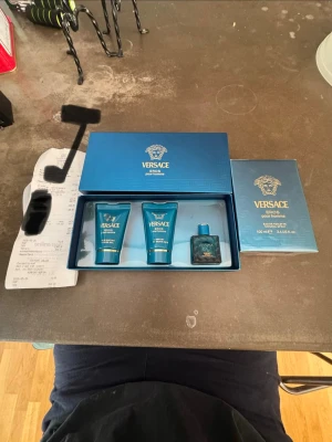 Versace Eros Pour Homme presentset - Snyggt presentset från Versace Eros Pour Homme med parfymflaska och två matchande blå tuber. Allt kommer i en lyxig blå ask med gulddetaljer och Versace-logga. Perfekt för dig som gillar exklusiva dofter och stilren design. Köpt från kicks, värde 1300. Både den 100ml flaskan till höger och presentkitet ingår. Allt är äkta och oöppnat 