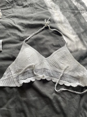 Vit virkad  topp - Superfin virkad vit linnetopp med halterneck och knyt i ryggen. Den är köpt i Grekland och använt en gång, den har insytt padding vid brösten också🥰