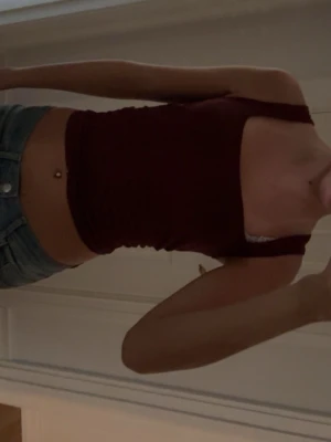 Mörkröd croppad linnetopp - Snygg mörkröd croppad linnetopp med breda axelband och tight passform. Perfekt till jeans eller kjol för en trendig look. Enkel och stilren design som passar till många outfits.