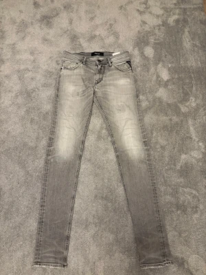 Ljusgråa slim jeans från Replay  - Säljer ett par ljusgråa slim jeans från Replay. Jeans med klassisk femficksmodell och slitna detaljer framtill. Jeansen har en smal passform och coola sömmar på bakfickorna. Perfekta för dig som gillar en avslappnad men trendig stil. Pris kan diskuteras vid snabb affär
