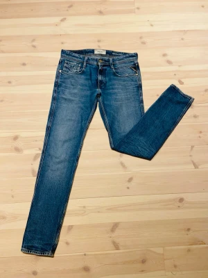 Blå slim fit jeans från Replay - Snygga blå slim fit jeans från Replay med klassisk femficksdesign och diskreta slitningar. Jeansen har normal midja och smala ben, perfekt för en trendig och avslappnad look. Materialet är mjukt denim som ger en bekväm känsla hela dagen. Mycket bra men använt skick(NY PRIS 1600kr). Va inte rädd för att fråga! Pris kan diskuteras!!