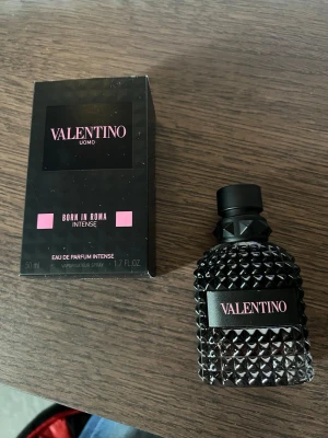 Valentino Uomo Born In Roma Intense - Valentino Uomo Born In Roma Intense är en lyxig parfym i en svart, nitar-inspirerad glasflaska med rosa detaljer. Flaskan rymmer 50 ml och har en modern, edgy design. Doften är en eau de parfum intense och levereras i en snygg svart kartong med rosa accenter. Ca 70-80 % kvar i flaskan