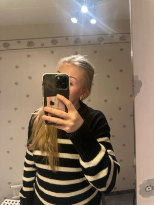 Svartvit randig stickad tröja - Snygg stickad tröja med breda svarta och vita ränder. Tröjan har en klassisk rund halsringning och långa ärmar med ribbstickade muddar. Perfekt för en avslappnad och trendig look.