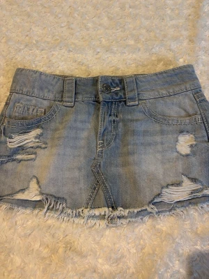 Ljusblå jeanskjol med slitningar - Säljer en kort ljusblå jeanskjol med slitna detaljer och fransig nederkant. Jätte fin men för liten🥰 Storlek xxs ifrån gina tricot 14+