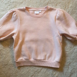 Ljusrosa kortärmad tröja Gina Tricot - Supersöt ljusrosa tröja från Gina Tricot med puffiga korta ärmar och har en mjuk känsla, perfekt till jeans eller kjol. Enkel och stilren design som passar till många olika looks🩷.