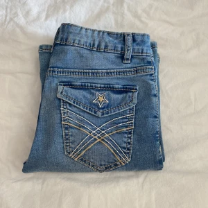 Blå bootcut jeans från Lindex - Snygga blå bootcut jeans från Lindex med coola bakfickor som har stjärnbroderi och kontrastsömmar❣️Klassisk femficksmodell i stretchig denim med normal passform och medelhög midja😇.