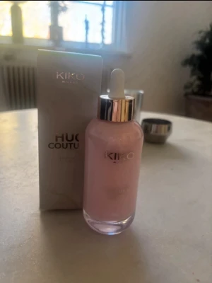 KIKO Milano Hug Couture Foundation - Bodyoil från KIKO Milano Kommer i en lyxig glasflaska med pipett och silvrigt lock. Färgen är ljusrosa med en lätt skimrande finish, perfekt för en fräsch och naturlig look. Oljan går att ha både som highlighter i ansikte och kropp, samt ha i håret som en hårolja. Det är en limited edition från KIKO. 