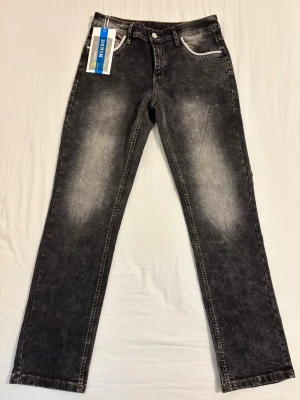 Svarta straight fit jeans med tvättad look - Säljer ett par svarta straight fit jeans med snyggt tvättad effekt och kontrastsömmar. Jeansen har fem fickor, bälteshällor och vita detaljer vid fickorna. Märket är Denim och materialet är bomull med stretch. Perfekta för en avslappnad och trendig stil.