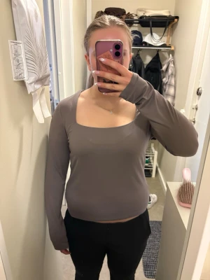 Brun långärmad topp från H&M - Säljer en stilren brun långärmad topp från H&M med fyrkantig ringning. Toppen har en slim passform och är gjord i mjuk bomullsmix som känns skön mot huden. Perfekt att matcha med både jeans och kjol.