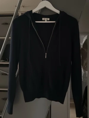 Marinblå hoodie från Soft Goat - Svart hoodie från Soft Goat i cashmere  med dragkedja framtill och  huva. Klassisk och stilren modell med långa ärmar och ribbade muddar. Perfekt för en avslappnad look.