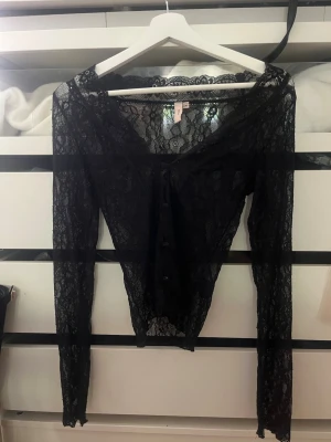 ❤️Svart spetsblus❤️ - Säljer en svart långärmad blus i genombruten spets med v-ringning och knappar framtill. Toppen har en figurnära passform och är perfekt för att lyfta vilken outfit som helst. Supersnygg att styla lager på lager eller med ett linne under.