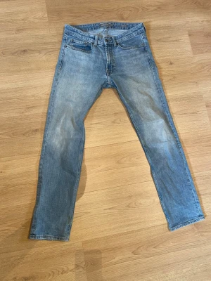 Ljusblå raka jeans från dressmann - Snygga ljusblå jeans med klassisk femficksdesign och raka ben. Jeansen har en normalhög midja och subtila slitningar framtill för en avslappnad look.                                                                                      Bara att höra av sig vid frågor om tex mått.                      Pris kan diskuteras vid snabb affär 