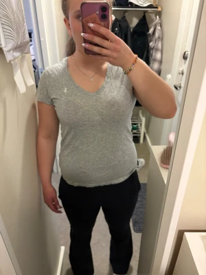 Grå v-ringad t-shirt från Ralph Lauren - Snygg grå t-shirt från Ralph Lauren med v-ringning och korta ärmar. T-shirten har en liten broderad logga på bröstet och är gjord i mjuk bomull. Perfekt till jeans eller shorts för en avslappnad stil.