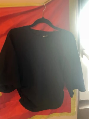 Svart topp med puffärm från Gina Tricot - Svart topp från Gina Tricot med rund halsringning och puffiga trekvartsärmar. Den är i storlek L men skulle säga att den passar S.Toppen har en lätt rynkad detalj i sidan och är tillverkad i mjukt bomullsmaterial. Perfekt för dig som gillar en stilren och trendig look.