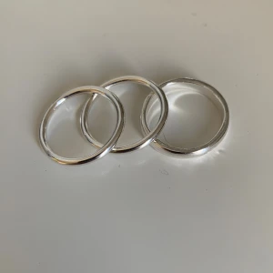 Set med silverfärgade ringar - Säljer ett set med sju stilrena ringar i silverfärg. Tre är enkla och släta, tre har tvinnad och bubblig design och en är bredare och klassiskt rund. Perfekta att mixa och matcha för en trendig look. De är i helt nytt skick och jag har aldrig andvändt de