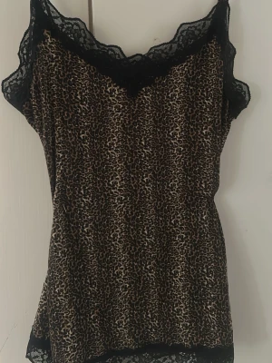 Leopardmönstrat  linne med spets - Snyggt linne med leopardmönster och svarta spetsdetaljer vid halsringning och nederkant. Tunn och mjuk modell med smala axelband, perfekt för att chilla hemma. Materialet känns lätt och bekvämt mot huden.