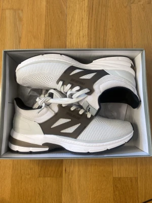 Vita sneakers från Polecat - Snygga vita sneakers från Polecat med grå detaljer och mesh-ovandel för bra ventilation. Skorna har en låg profil, vita snören och en bekväm sula som passar perfekt till en sportig och avslappnad stil. Perfekta för dig som gillar stilrena och moderna sneakers.