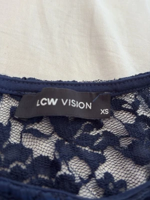 Blå spetsblus från LCW  - Säljer en blå blus från LCW  i storlek XS. Blusen är helt i spets med blommigt mönster och har korta ärmar. Perfekt för dig som gillar en feminin och trendig look. Materialet är lätt och luftigt, vilket gör den skön att bära.