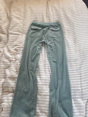 Mintgröna velourbyxor Juicy Couture - Säljer ett par mintgröna mjukisbyxor från Juicy Couture i mjuk velour. Byxorna har utsvängda ben, två bakfickor med knappar och bred resår i midjan. Perfekta för en chill och trendig look.💓💓