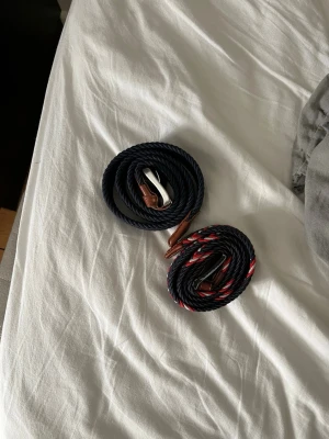 Två flätade bälten blått helt nytt från Jack and Jones, de andra använt men inte sämre för det. - Säljer två snygga flätade bälten med läderdetaljer och metallspänne. Det ena är mörkblått och det andra har ett randigt mönster i mörkblått, rött och vitt. Perfekt för att ge outfiten en cool touch.
